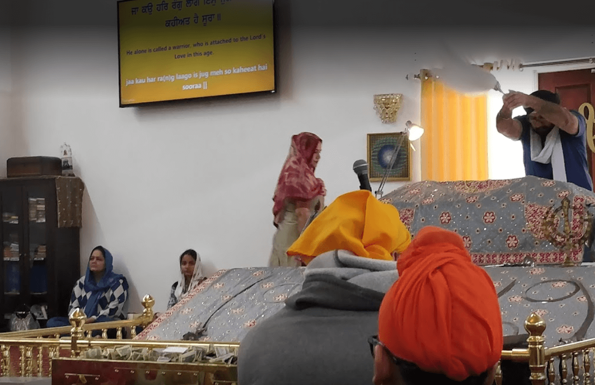 Sangat gathered in the Darbar Sahib during a diwan, with Chaur Sahib being waved over Guru Granth Sahib Ji