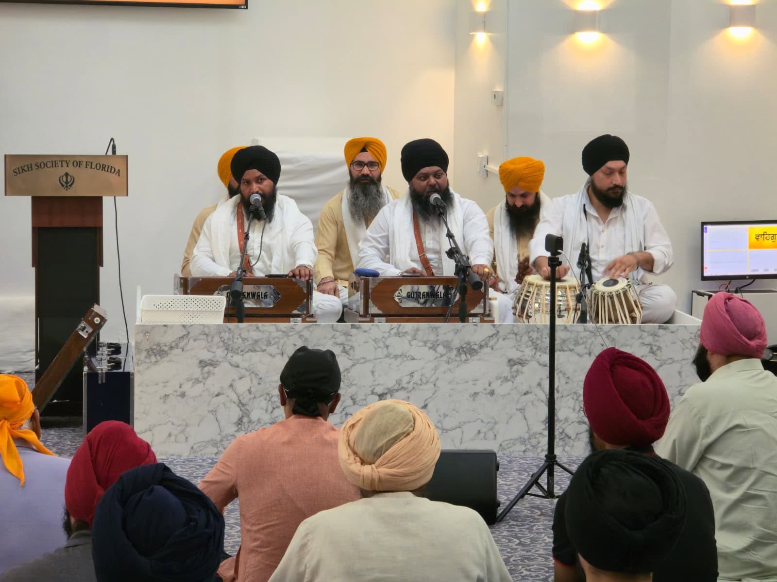 The golden Palki Sahib enshrining Guru Granth Sahib Ji, adorned with flowers and Chaur Sahib